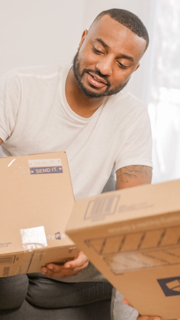 Bearded man holding and sorting packages at home, ideal for delivery or logistics themes.